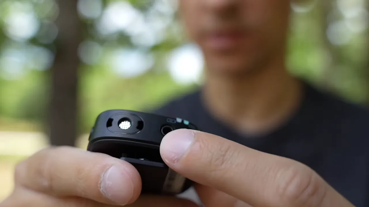 Finger pointing at the 3.5mm lavalier input on the Maono WM820 transmitter