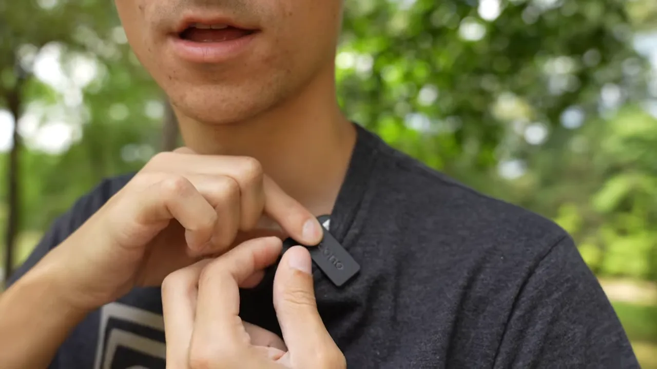 Close-up of hands clipping Maono WM820 transmitter to shirt near the collar
