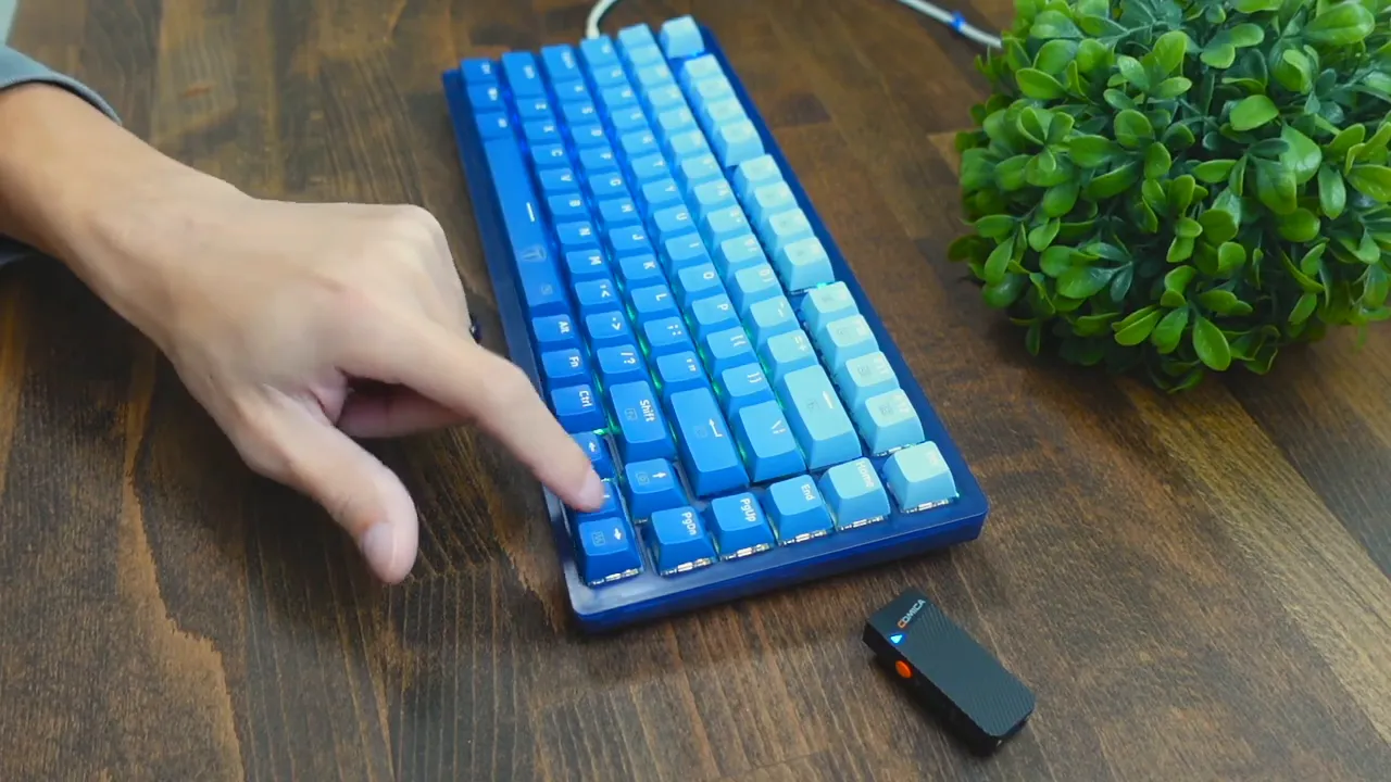 Finger pressing a function/media key on the RisoPhy TKL 75% keyboard with gradient blue keycaps