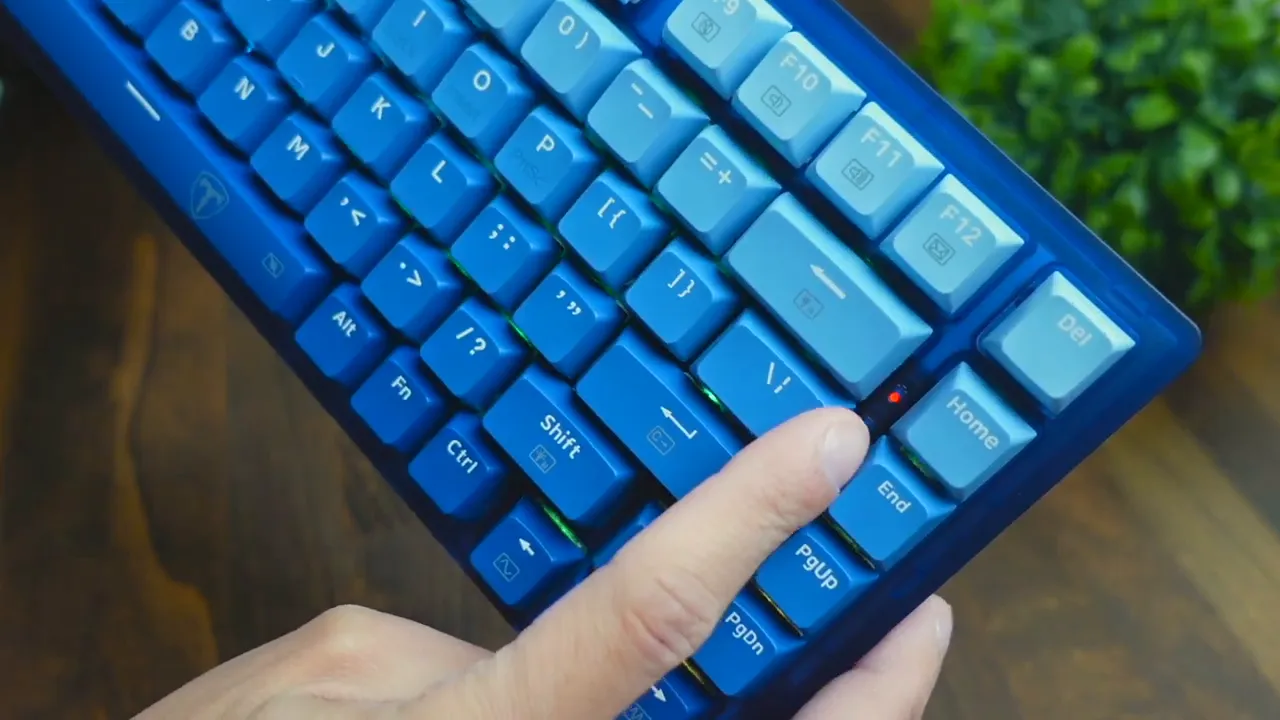 Finger pressing near the small status LED and function keys on the RisoPhy TKL 75% keyboard with gradient blue keycaps