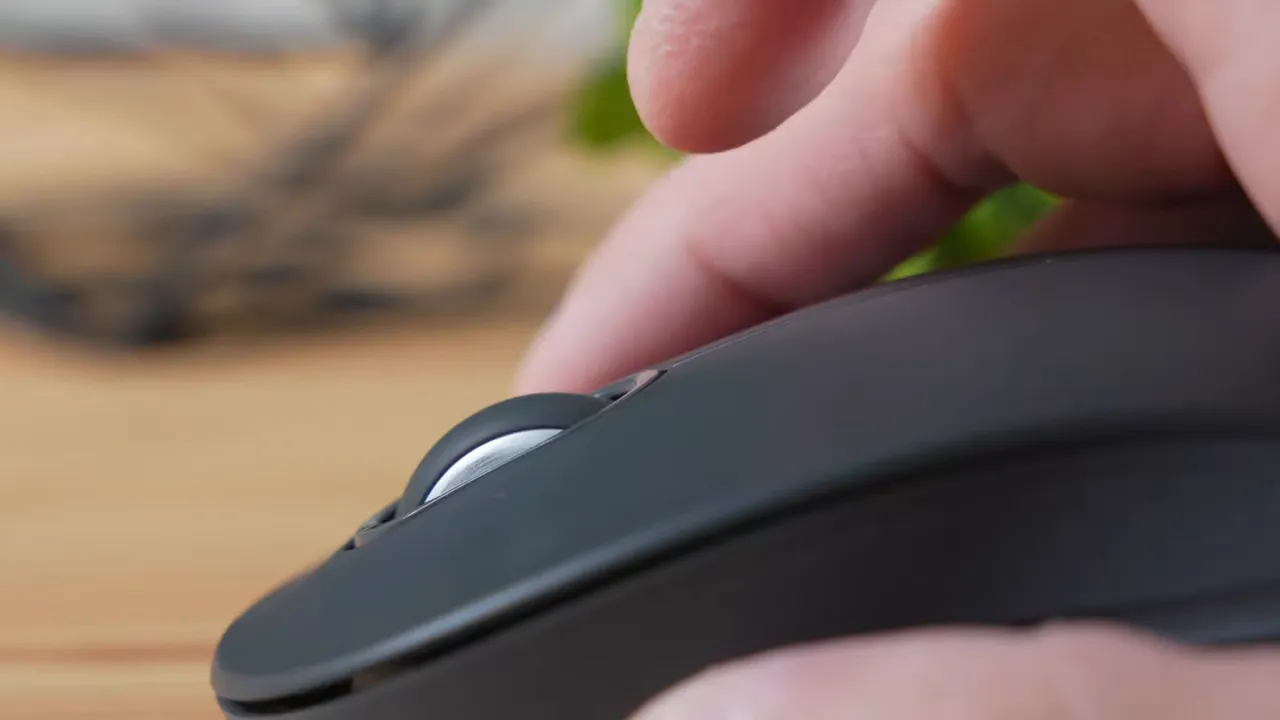 Side view of a finger flicking the Logitech M550 scroll wheel to demonstrate free-spin