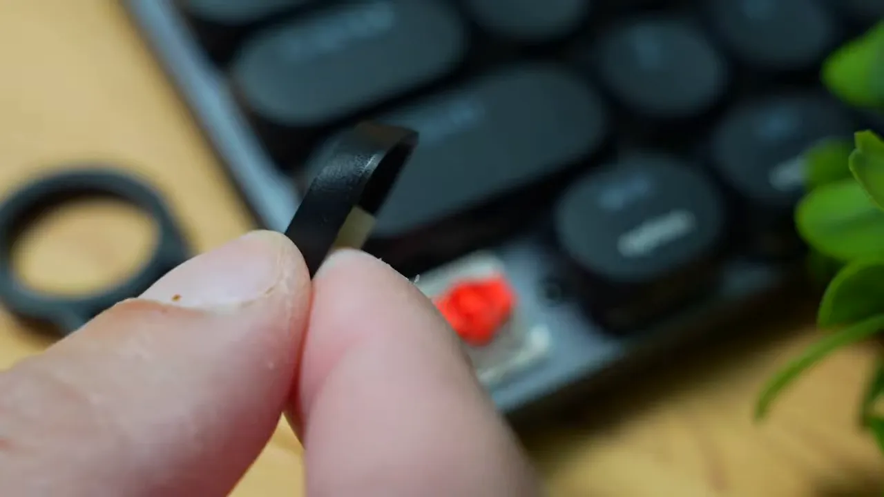 Fingers removing a keycap to reveal a red mechanical switch on the ProtoArc MECH K300 keyboard.
