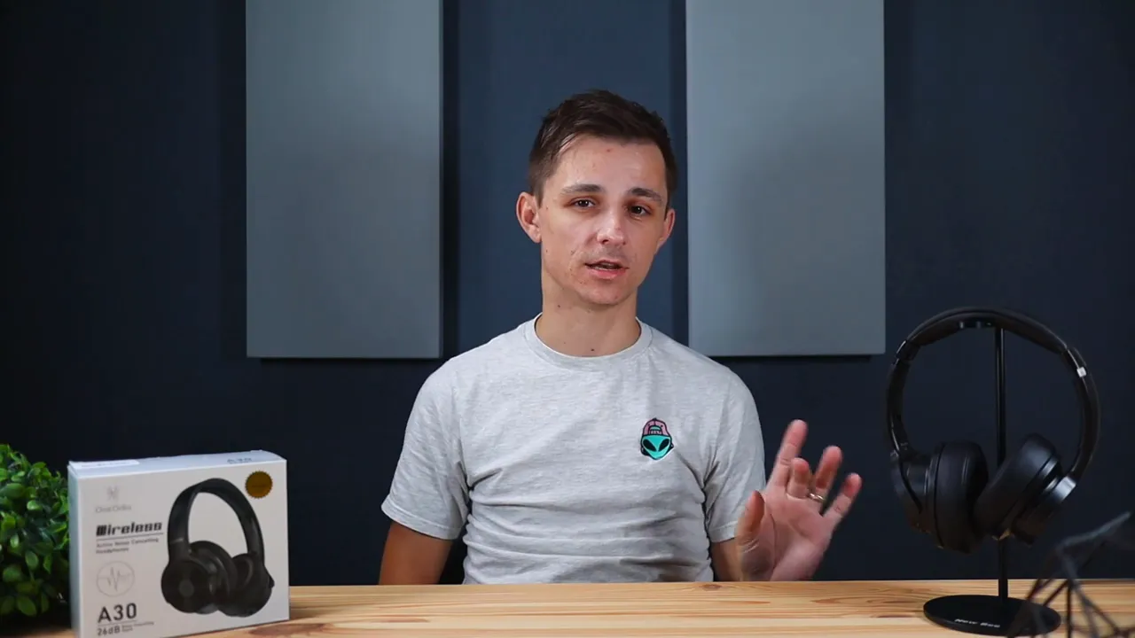 Presenter describing sound with OneOdio A30 headphones on a stand and packaging on the table