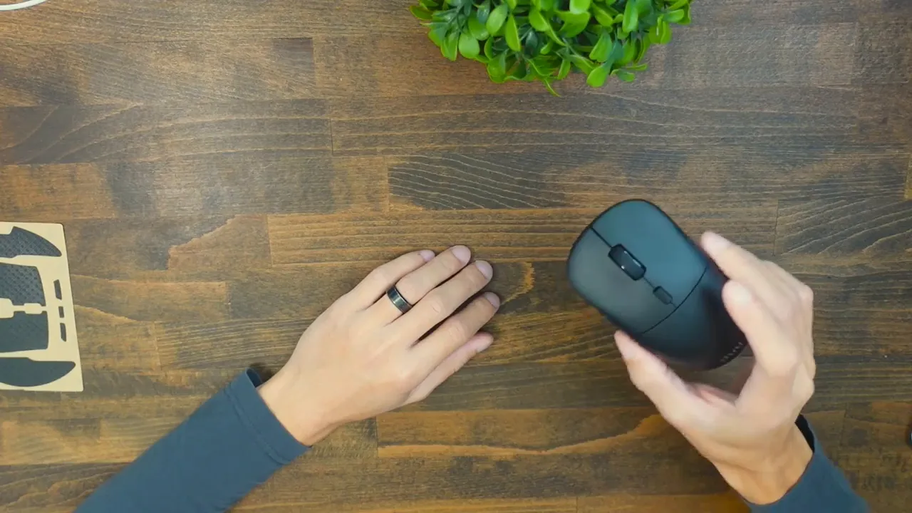 Top-down view of Uhuru WM-09 held in hand over a wooden desk with a sheet of grip tape visible