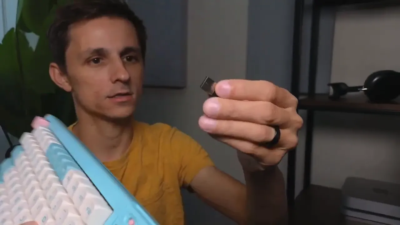 Person holding the DUSTSILVER D84 2.4 GHz USB dongle next to the keyboard