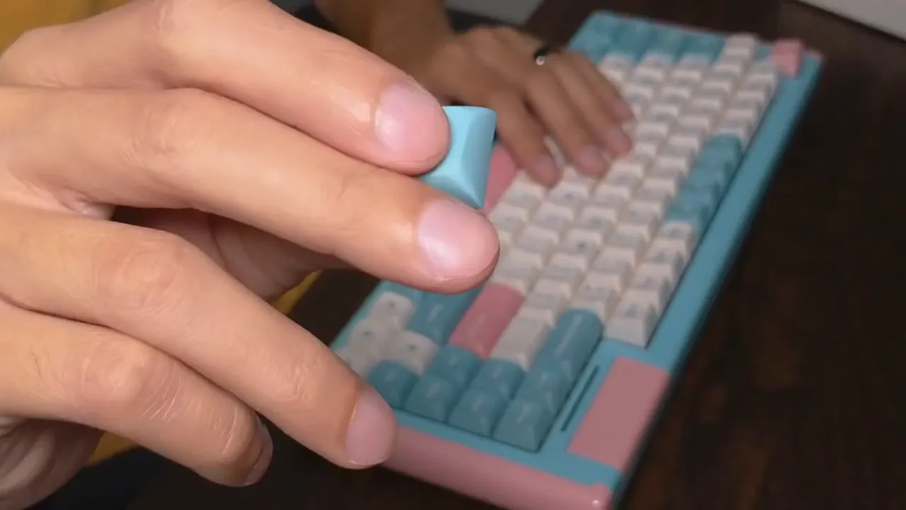 Hand holding a blue PBT keycap above the DUSTSILVER D84 keyboard showing the keycap profile and texture