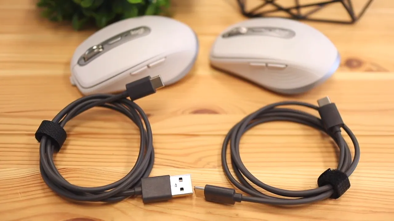 Two charging cables on a wooden desk with two MX Anywhere mice in the background
