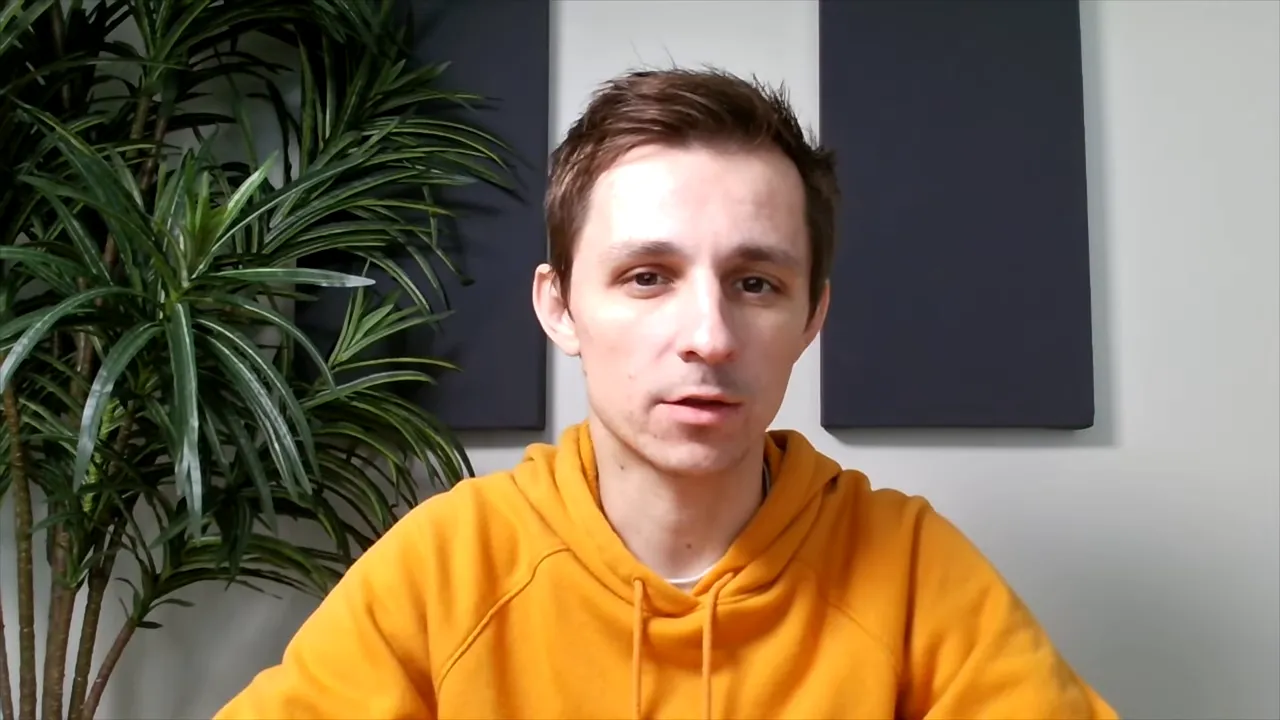 centered shot of person in orange hoodie facing camera with plant and acoustic panels behind