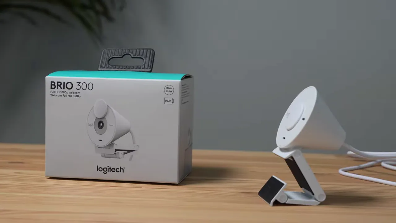 Logitech Brio 300 box and white webcam displayed on a wooden table