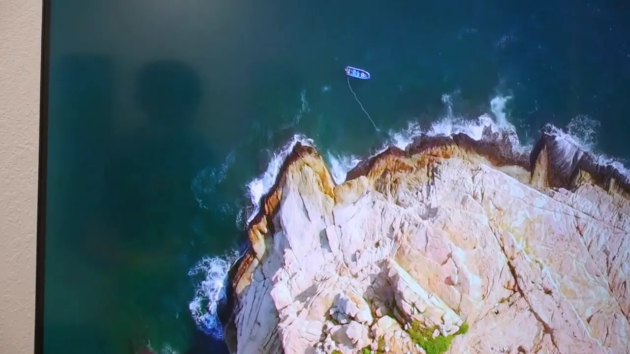 Aerial coastline scene displayed on the TV with green water and rocky shore