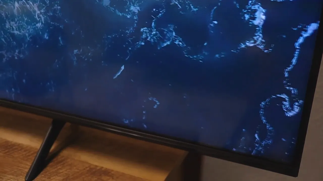 Front corner of the TV showing thin side bezels and lower bezel above the stand leg