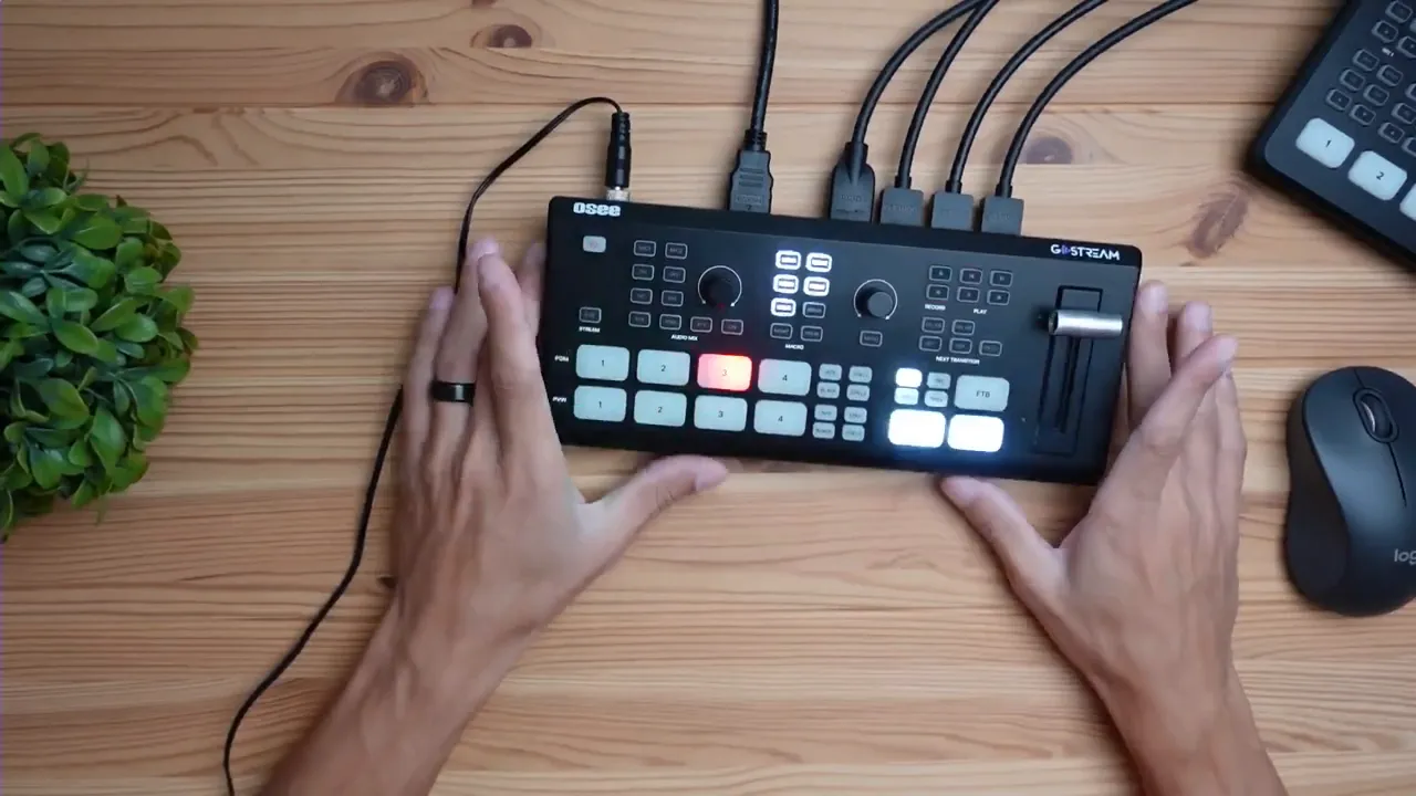 Clear top-down view of the OSEE GO-Stream Deck with numbered input buttons illuminated and hands beside the unit