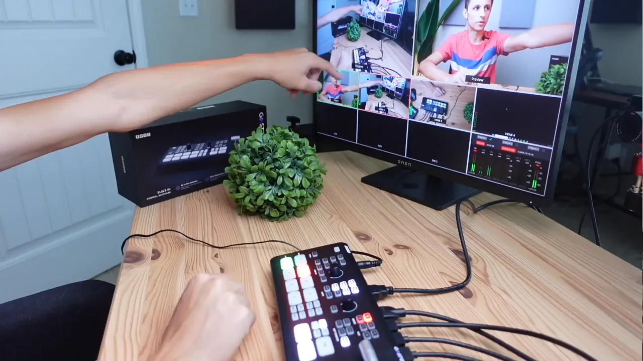 Desk setup with GO-Stream Deck, cables and a monitor showing program and preview multiview while an arm points at the screen.