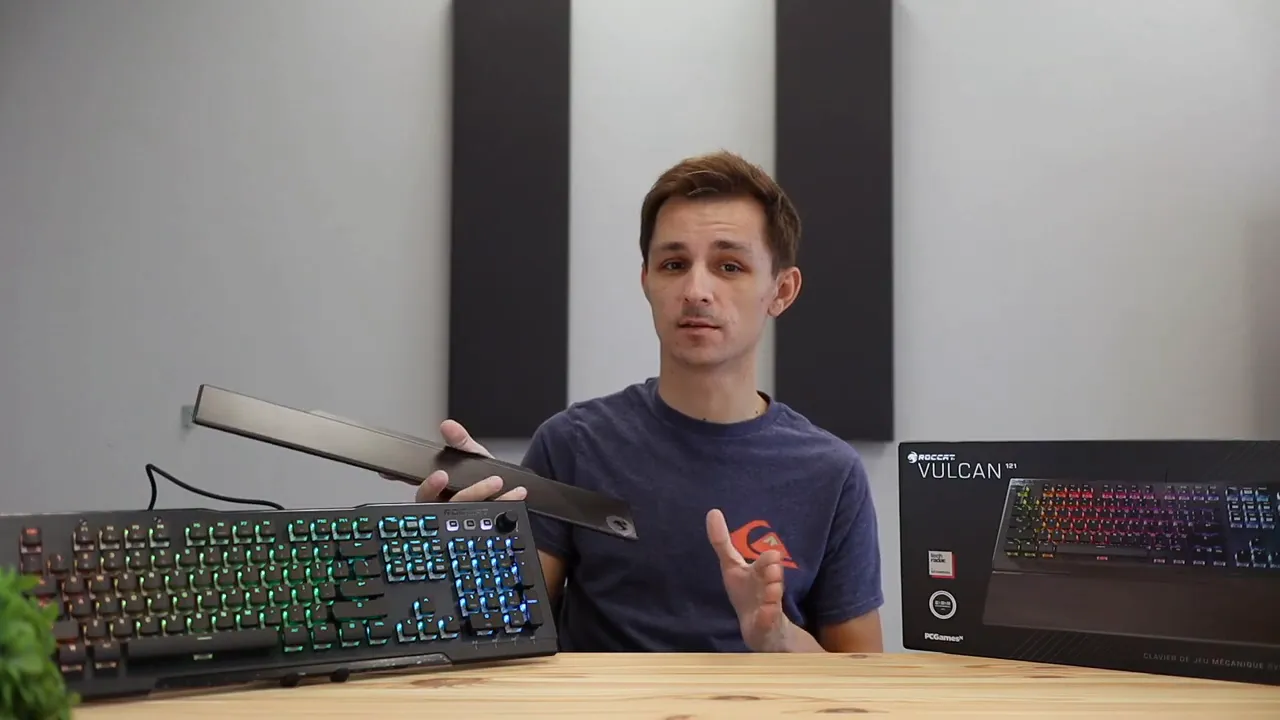 Keyboard attached to a wide black wrist rest on a wood desk