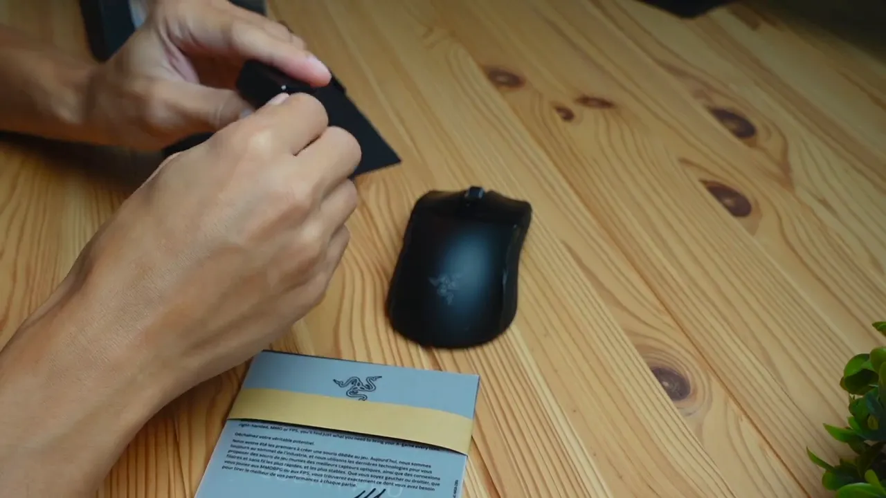 Razer Cobra Pro mouse on a wooden desk with documentation and hands during unboxing