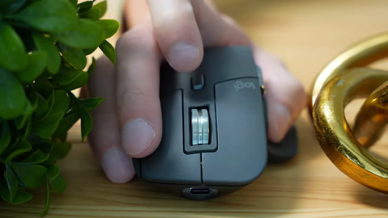 Logitech MX Master 3s metal MagSpeed scroll wheel with a finger positioned near the mode switch behind the wheel