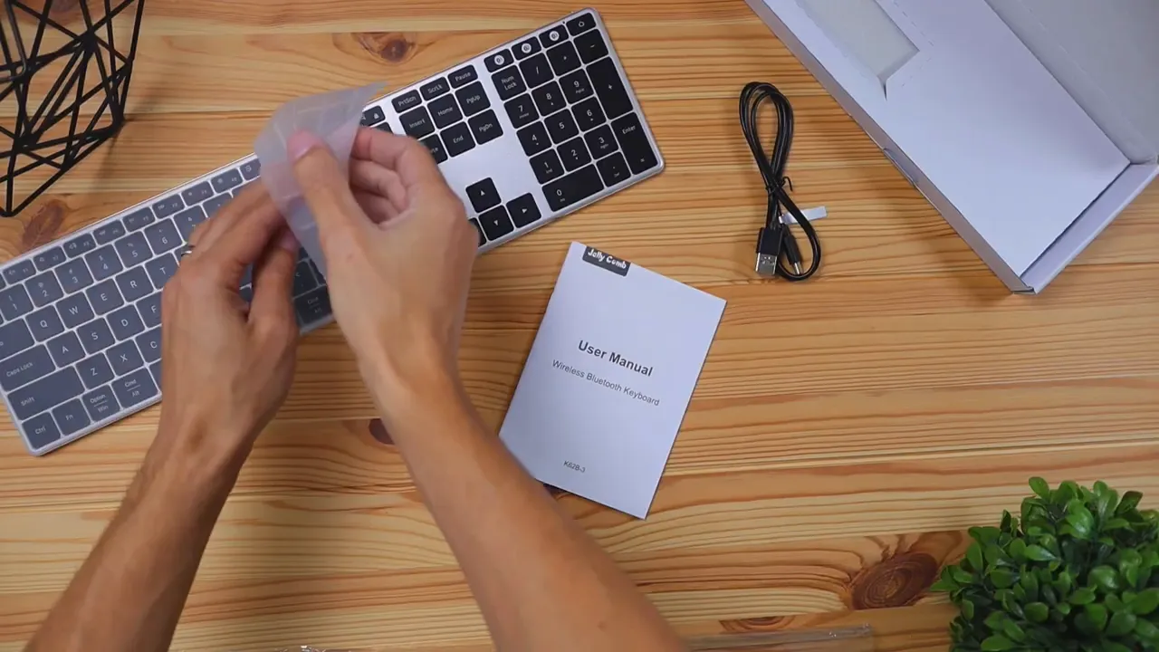 overhead view of Jelly Comb K62BA-3 keyboard, user manual, USB-C cable and packaging on a wooden desk