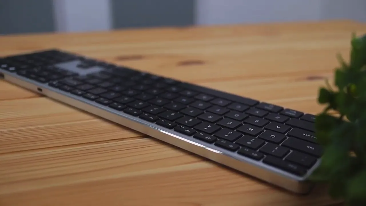 Full-length side view of the Jelly Comb K62BA-3 keyboard on a wooden desk, showing the thin aluminum edge and low-profile keys.