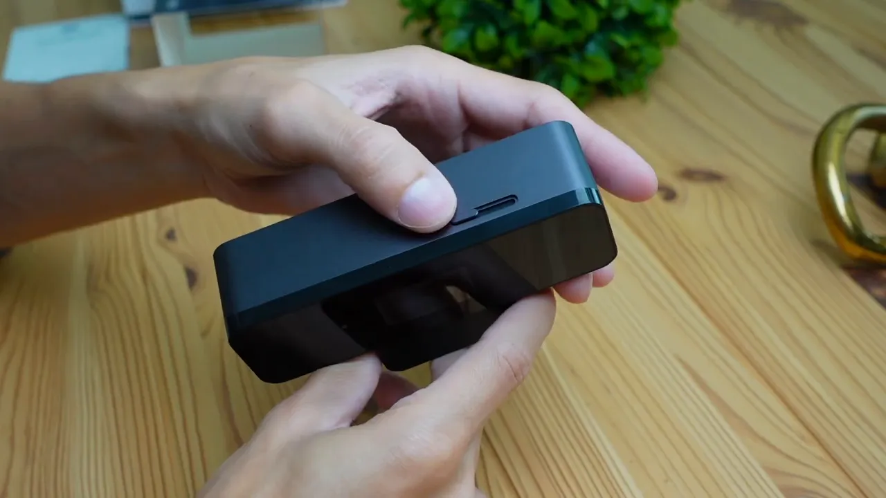 Close-up of the Coolpo Mini Lite showing the manual privacy shutter slider and clip held in hands