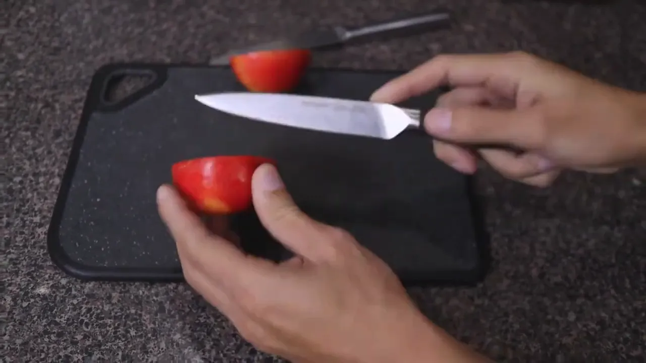 Apple cut cleanly into pieces on a black cutting board with the utility knife nearby