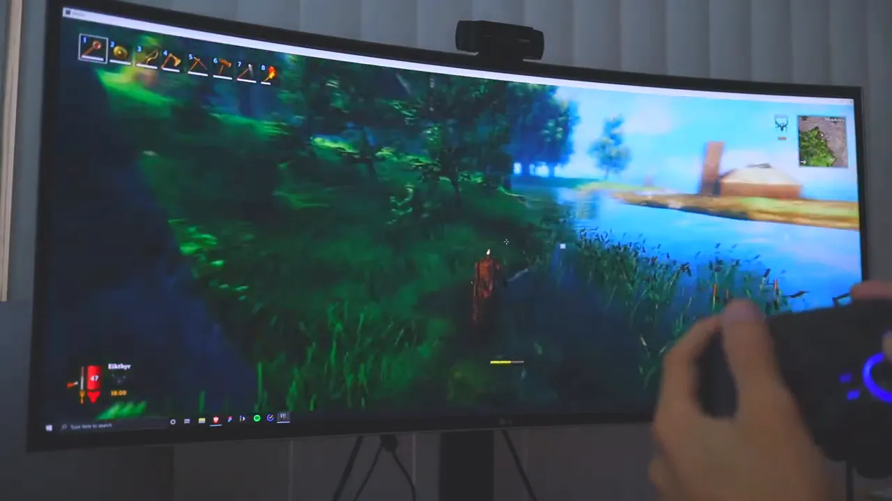 Player holding EasySMX ESM 9110 controller while playing a game on a curved monitor
