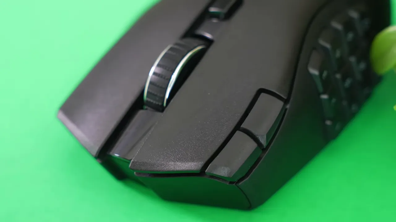 Detailed Razer Naga V2 close-up showing the textured scroll wheel, left-front buttons, and thumb grid on a green background.