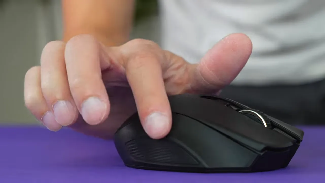 Finger resting on Razer Naga V2 showing ring-finger indent and textured pinky area