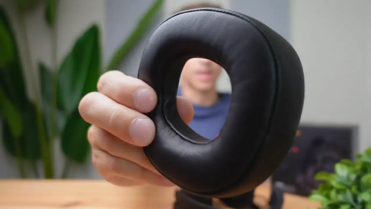 Close-up of a Senzer SG500 synthetic leather ear pad held in hand, highlighting the removable design and material