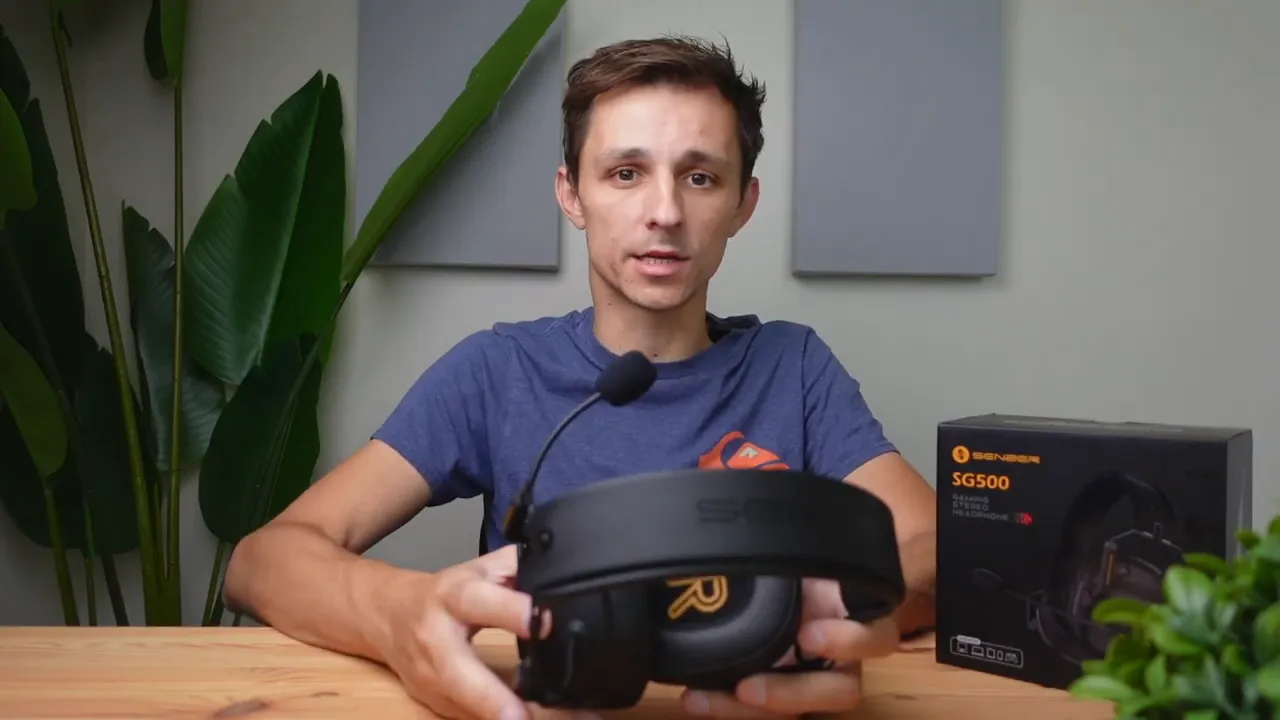 Close-up of Senzer SG500 headset held on a table, showing the boom microphone with foam windscreen and the product box in the background.