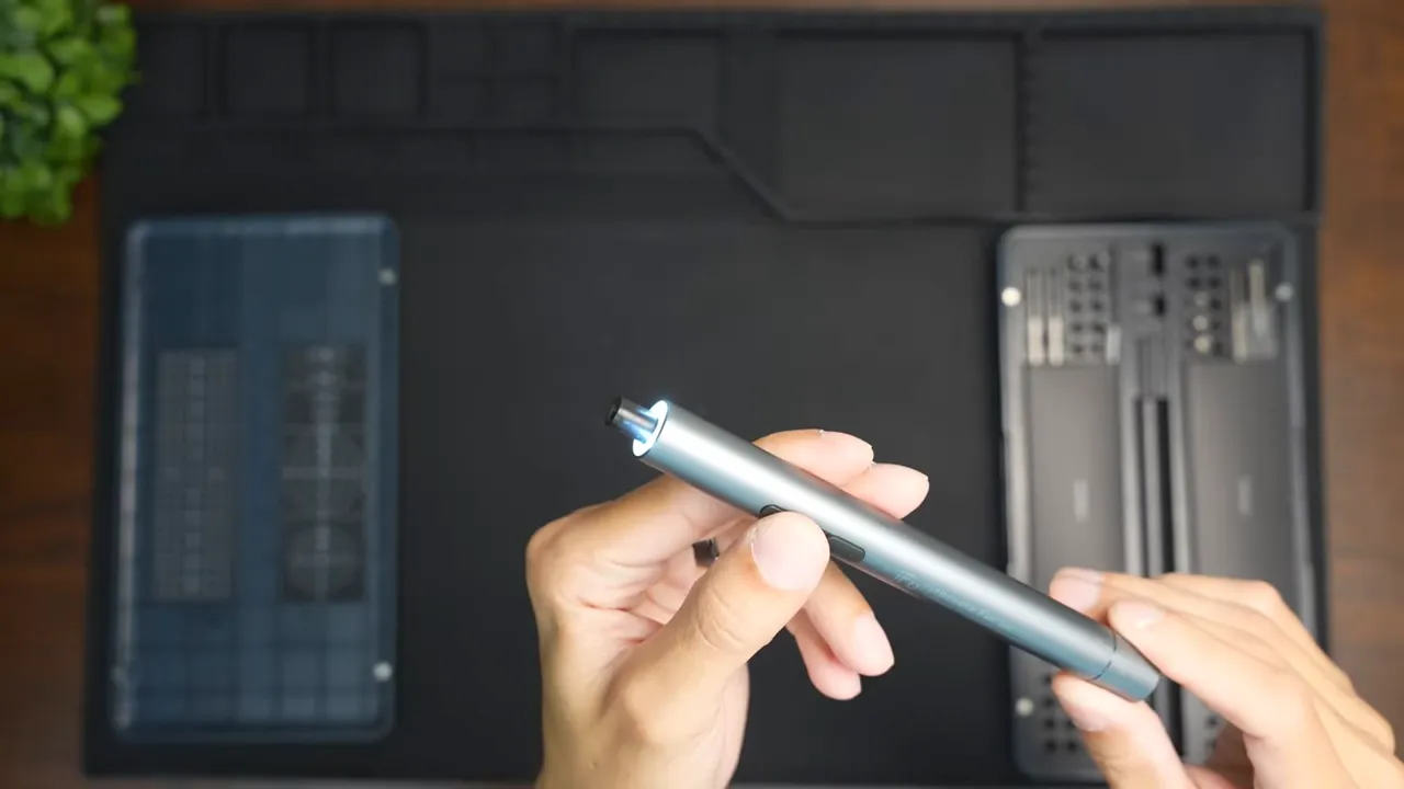 iFu pen-style electric screwdriver held in hands with the front LED illuminated next to the bit