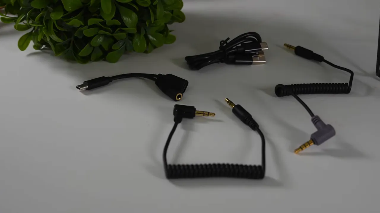 Assorted audio cables and adapters included with the Comica Vimo C3 laid out on a table