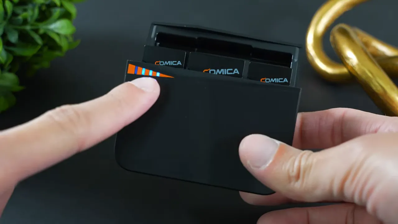 Comica Vimo C3 charging case opened with LED battery indicator lit and transmitters inside