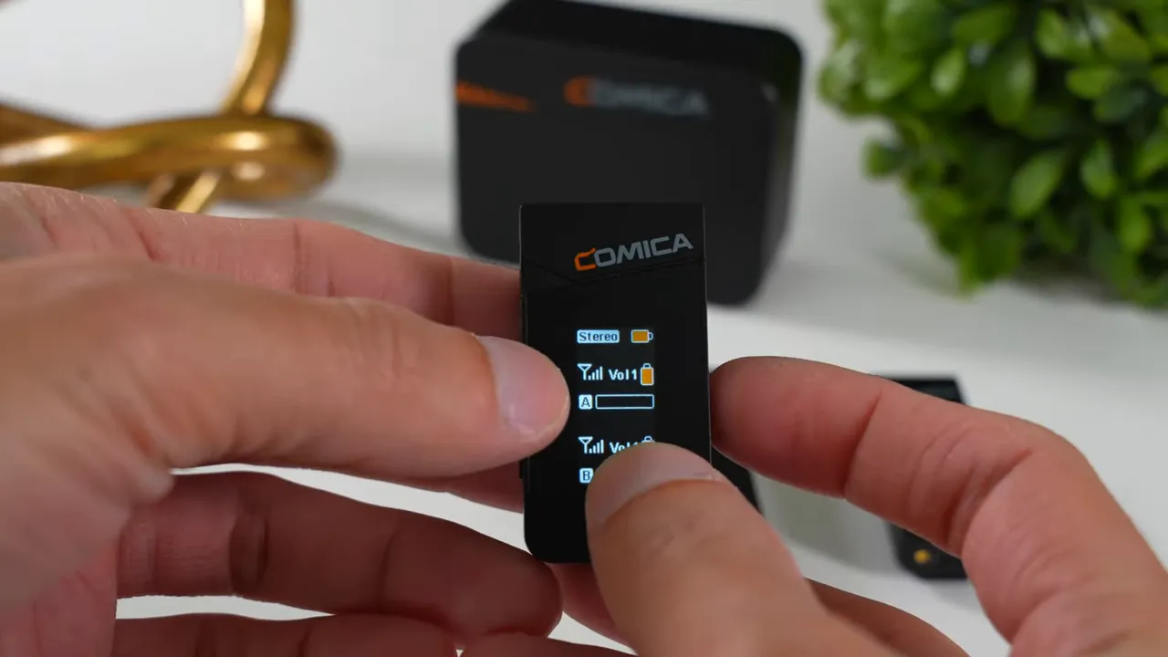 Comica Vimo C3 transmitter screen clearly showing 'Stereo', volume bars and battery icon while a thumb interacts with the control.