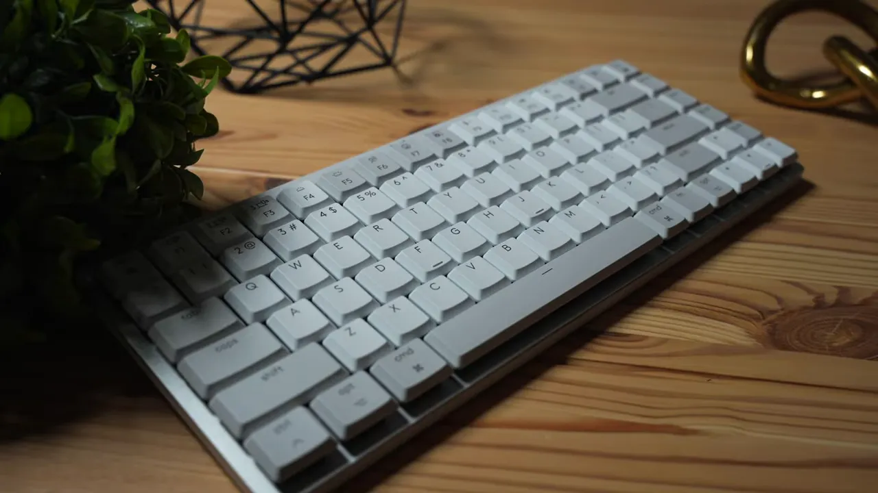 Full view of the Logitech MX Mechanical MINI keyboard on a wooden desk showing keycaps and aluminum top