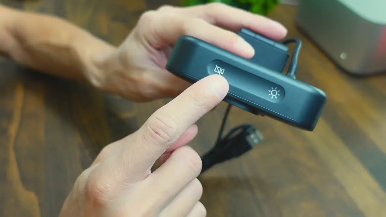 Finger pressing the mute button on the NUROUM V32AFL webcam, clearly showing the top control icons