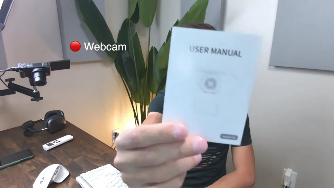 User holding a close-up user manual up to the webcam to demonstrate autofocus