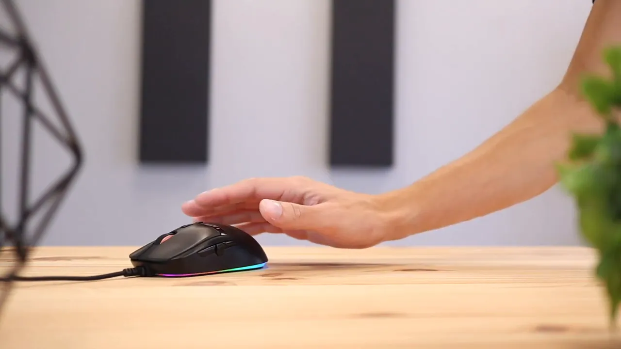 Hand resting flat on the gaming mouse on a wooden desk