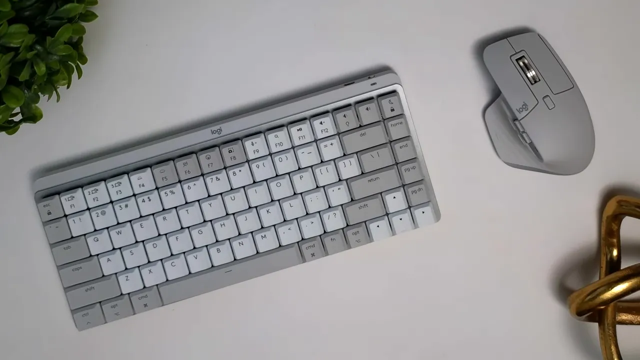 Logitech MX Master 3s mouse in pale gray next to a compact matching keyboard on a white desk