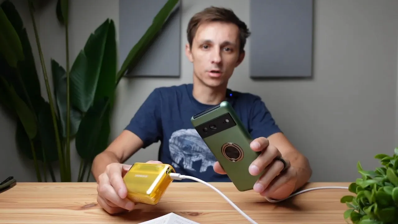 Starship Seer transparent yellow power bank connected to a phone via USB cable on a wooden table, clear focus on the devices