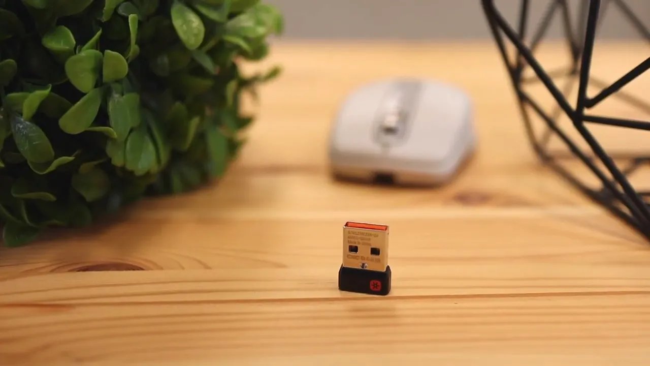 USB wireless receiver standing on desk with mouse blurred in background