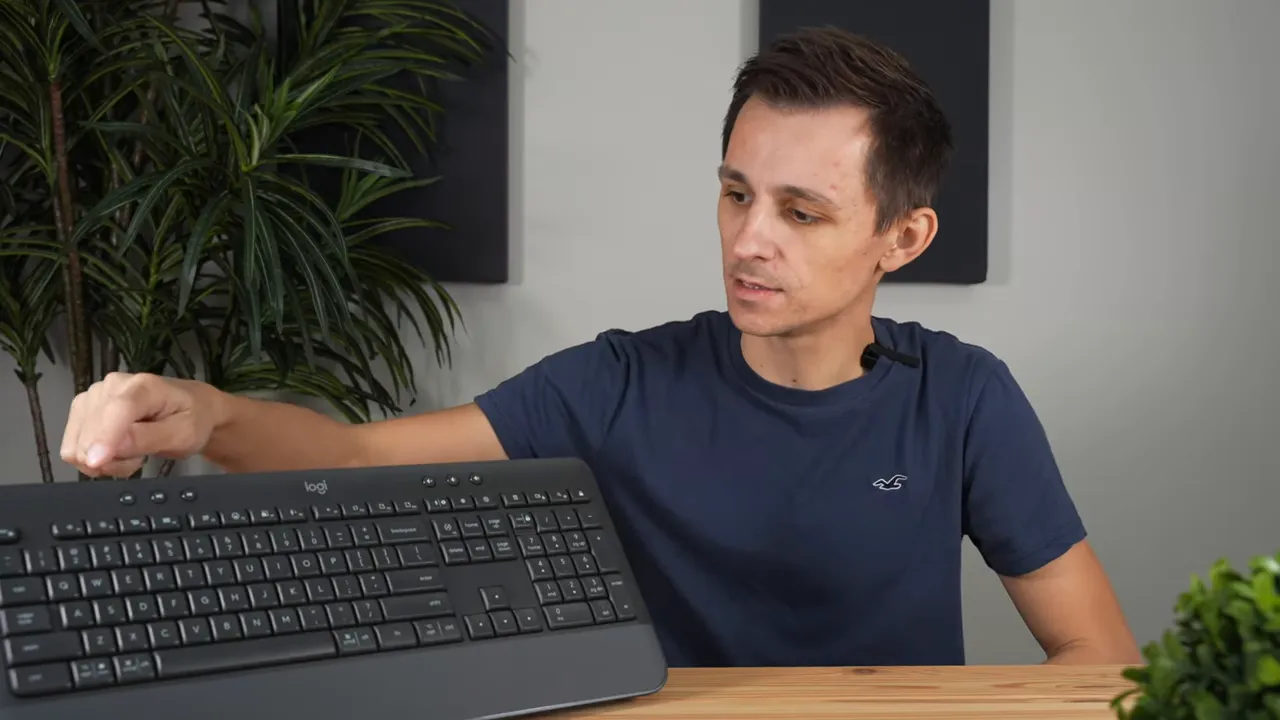 Reviewer pointing at the top-row media and browser shortcut keys on the Logitech K650