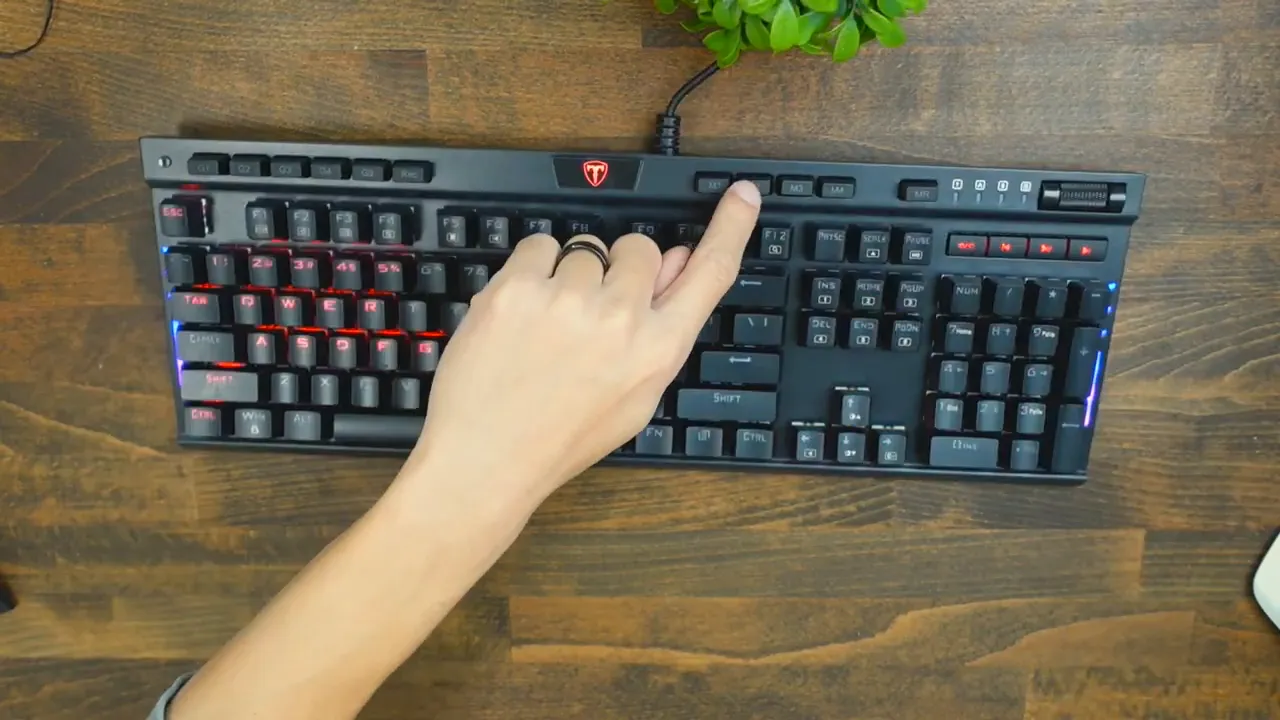 Finger pressing M profile button on Risophy keyboard to change lighting profiles and modes