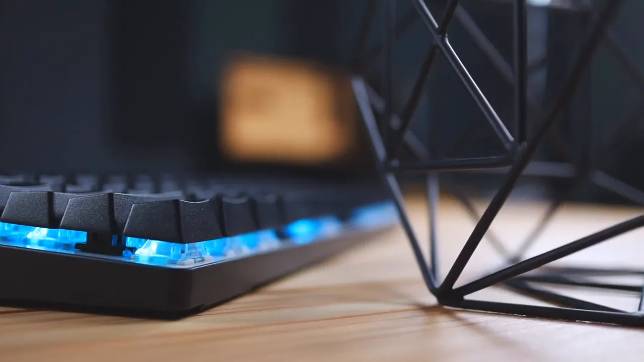 Side-profile close-up of Atom 60% keyboard showing blue switches and bright RGB underglow on a wooden desk