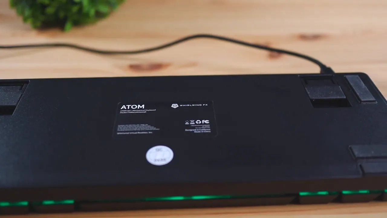 Full view of the Atom keyboard bottom showing flip-out legs, rubber feet and product label