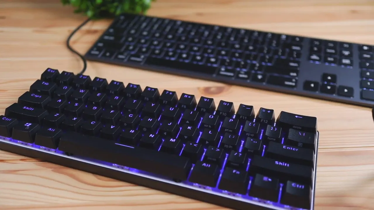 Atom 60% compact mechanical keyboard in foreground with full-size keyboard behind for size comparison
