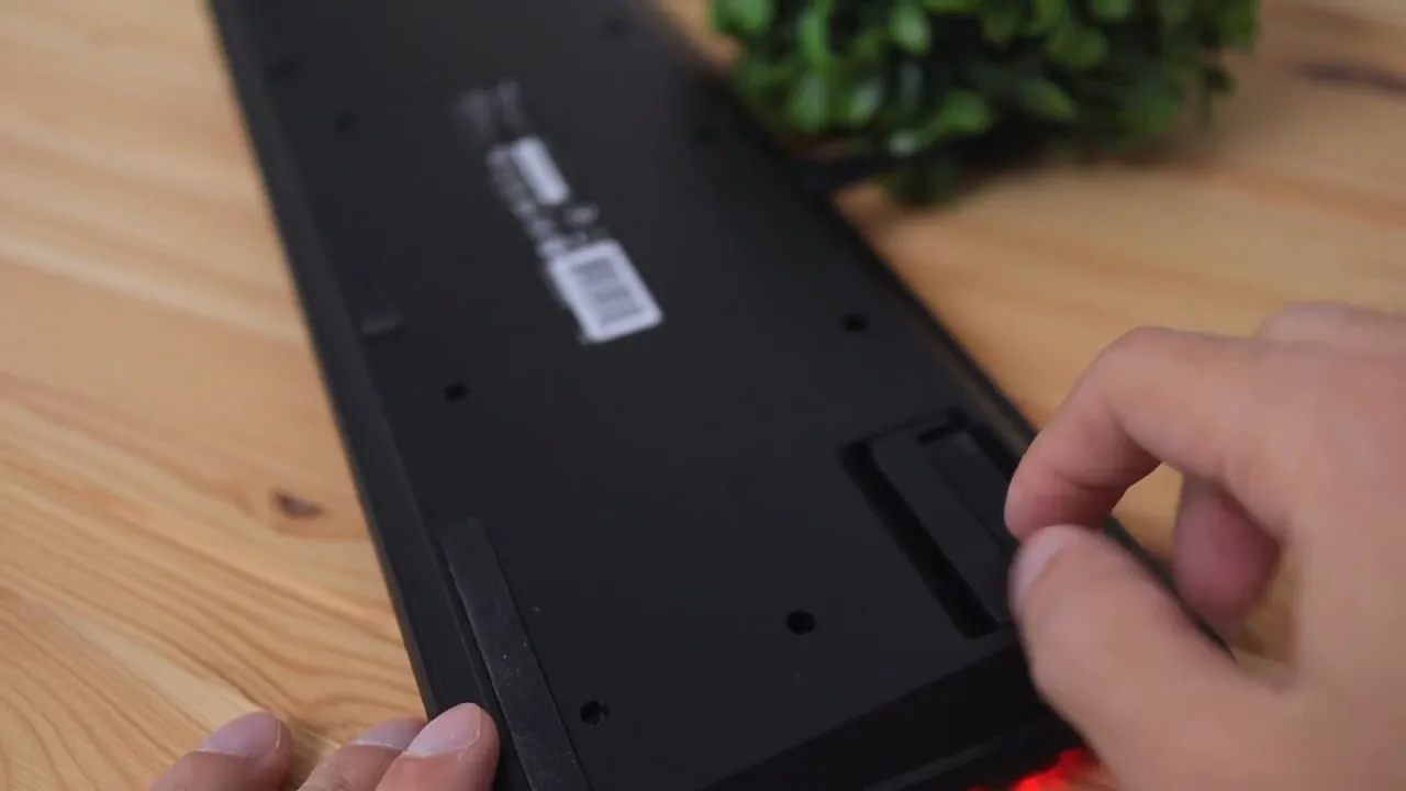 Hand adjusting one of the rear kickstand legs on the underside of the keyboard