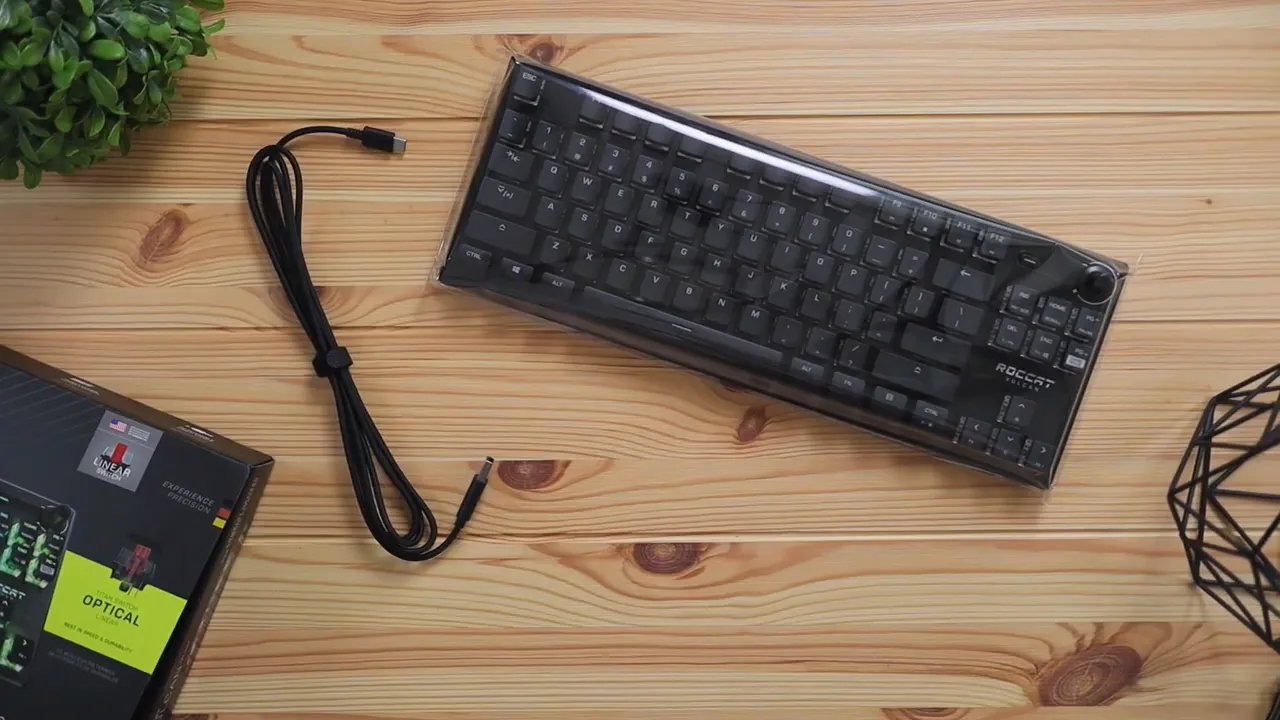 Quick start guide held above keyboard and cable on wooden desk