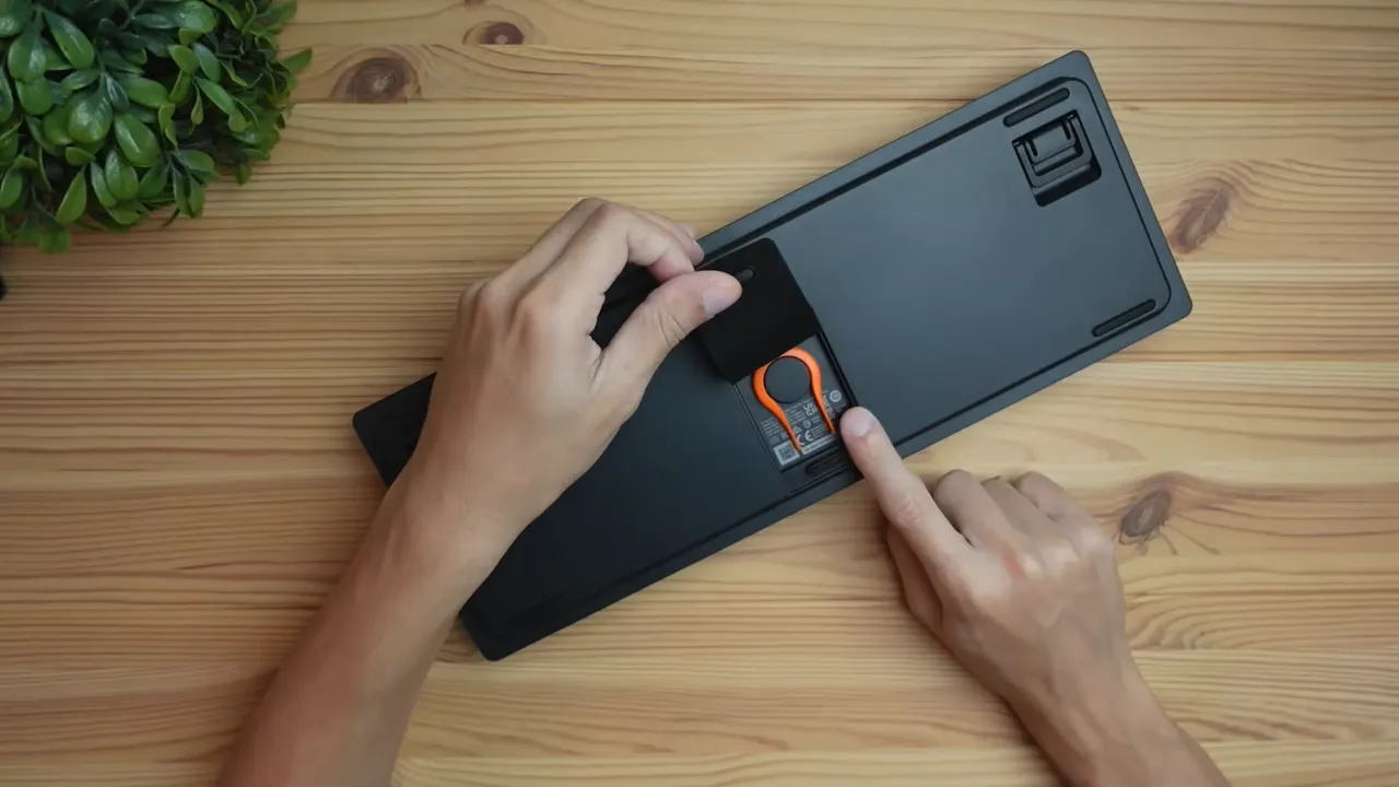 SteelSeries Apex 9 TKL underside with magnetic cover open exposing the orange keycap puller and rubber feet