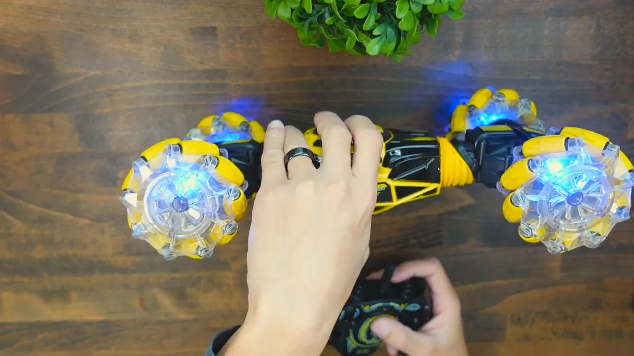 Top-down view of the DoDoeleph RC car showing clear detail of the blue LED-lit mecanum-style wheels and a hand holding the controller.