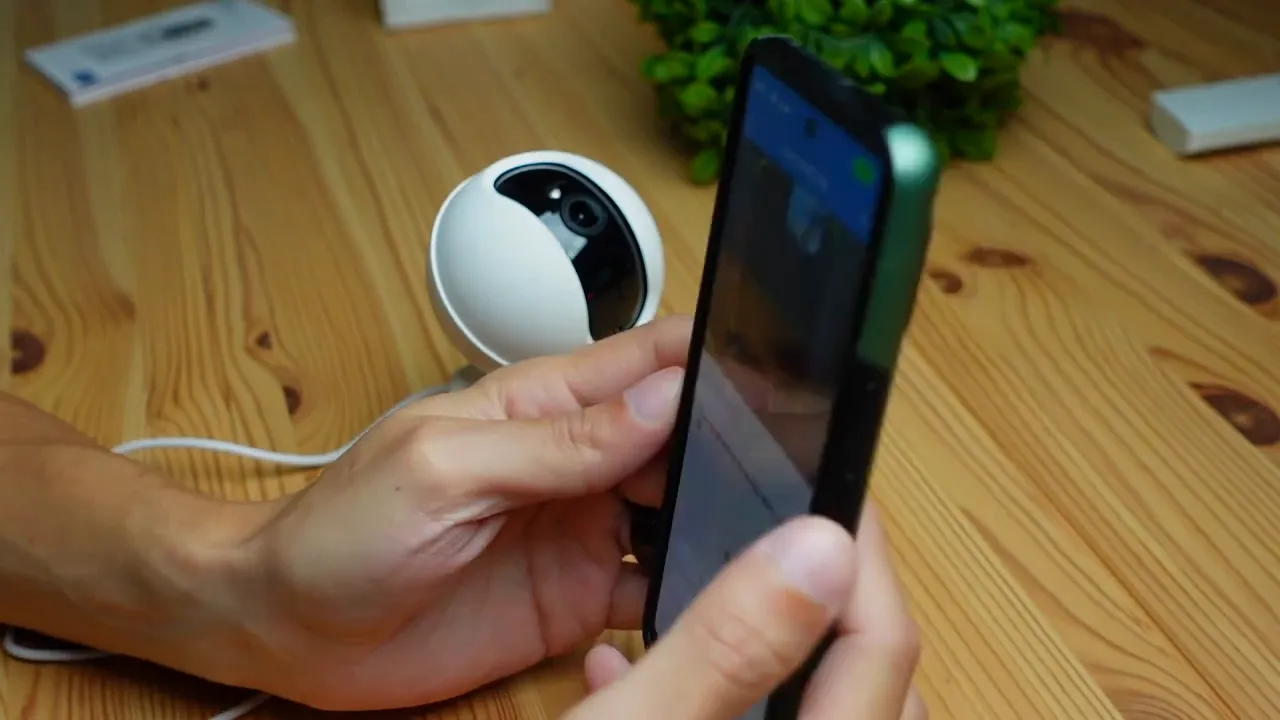 Hands holding smartphone next to Annke Creator Pro camera while setting up the app